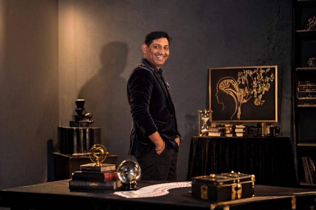 Vikram Singh smiling in a dim, book-lined study with a crystal ball and a fanned deck of cards on the table